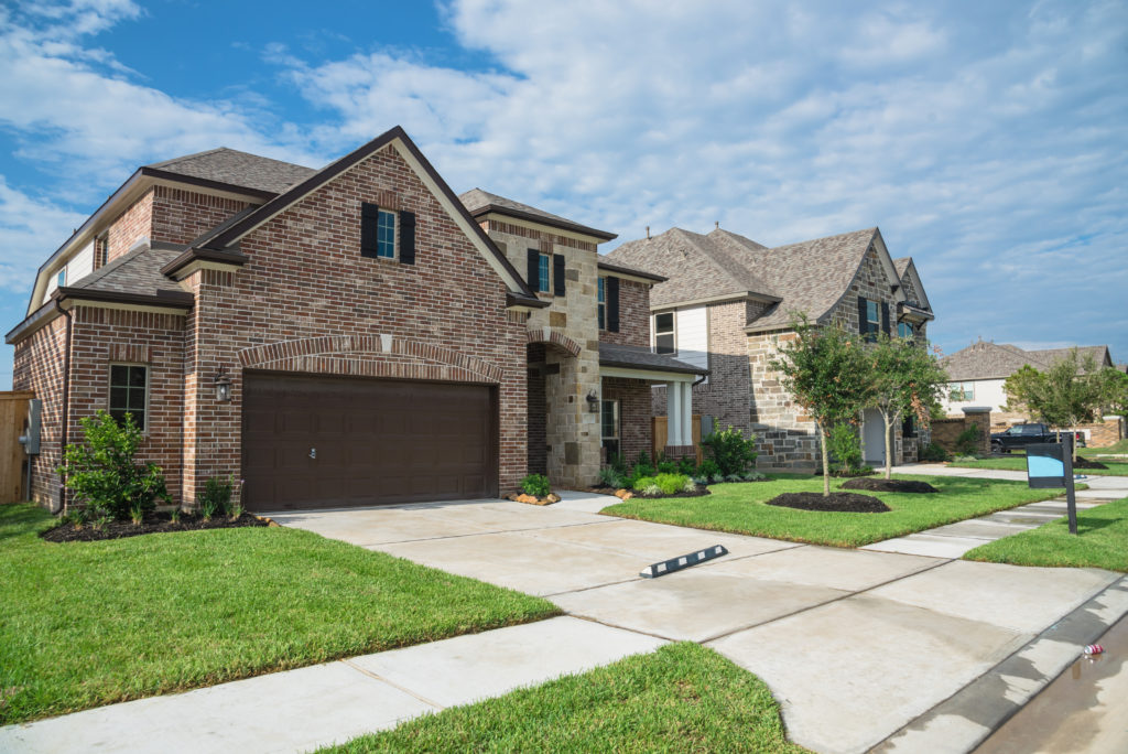 A large brick house with a garage in the front yard